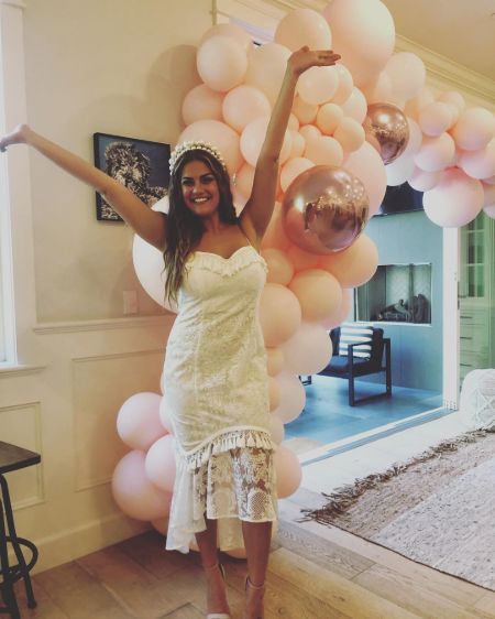 Actress Katie Maloney in a white dress poses a picture.